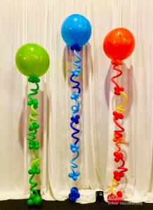 3 big balloons, one blue, one green, one orange, all connected to ground by swirly balloons.