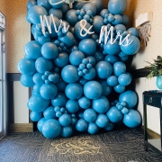 A balloon wall display of blue balloons with the sign"Mr. & Mrs." at the top