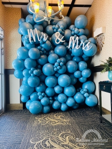 A balloon wall display of blue balloons with the sign"Mr. & Mrs." at the top