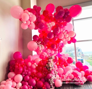 variety of pink balloons and flowers cascading up wall in display