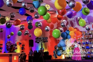 silver and rainbow assorted balloons individually hung from ceiling above dance floor.