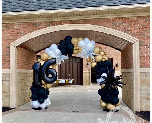 a black, gold, and white balloon arch with the numbers 16 on the side.