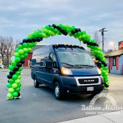 A green and black balloon arch above a ram van.
