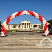 a white and red balloon arch in front of a memorial building.