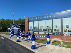 A blue and white balloon arch over a walkway that is strung to a blue and white column on either side.