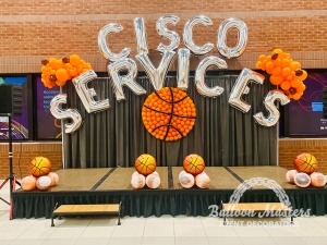 the words "cisco services" arched across stage with a balloon basketball underneath and basketball themed balloon bunched spread on stage