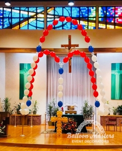 red, white, gold and blue balloons creating a giant rosary on a church altar.