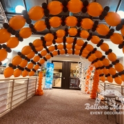 multiple black and orange balloon arches spaced over walkway