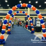 five blue, orange, and white balloon arches along walkway.