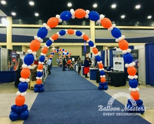 five blue, orange, and white balloon arches along walkway.