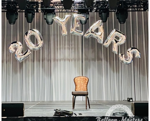 The text "20 years" strung in arch above stage in silver lettering.