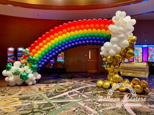 A rainbow balloon display with green clovers on one side and gold balloons on the other.