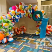 A summer balloon arch made of beach balls and pool floaties.