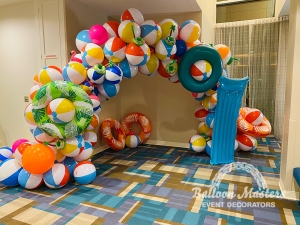 A summer balloon arch made of beach balls and pool floaties.