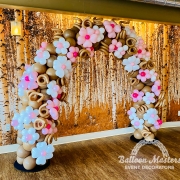 A brown balloon arch covered in white and pink little balloon flowers.