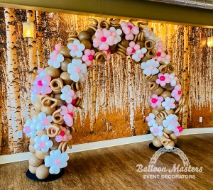 A brown balloon arch covered in white and pink little balloon flowers.