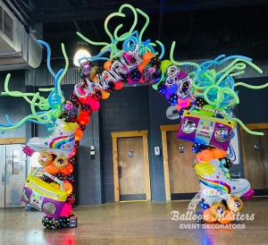 a neon and black polka dot arch covered in 80s themed balloons like roller skates, boom boxes, and swirly green and blue fly-off balloons.