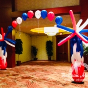 red white and blue balloon columns with blue red and white strung to make arch shape.