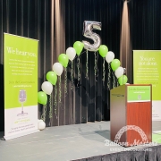 green and white singular balloons arranged in arch formation with the number 5 at peak