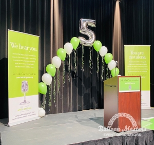green and white singular balloons arranged in arch formation with the number 5 at peak
