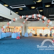 rose gold, white, and clear singular balloons arranged in two arch formations that overlap creating a cross shape.