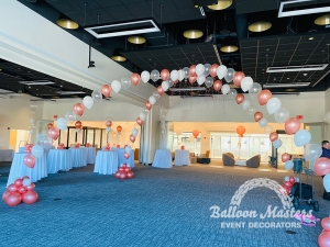 rose gold, white, and clear singular balloons arranged in two arch formations that overlap creating a cross shape.
