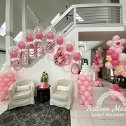 baby pacifiers made from balloons attached to two pink baby bottle shaped balloon columns with two pink flower balloon bouquets to the right