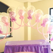 pink and purple balloons blown up inside clear balloons arranged in arch formation