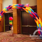 A blue, purple, blue, orange and yellow balloon arch.