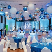 silver, white, and blue balloons individually hung from ceiling above circular tables and dance floor.