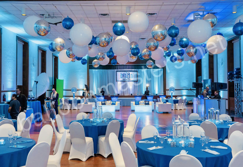 silver, white, and blue balloons individually hung from ceiling above circular tables and dance floor.