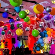 silver and rainbow assorted balloons individually hung from ceiling above dance floor.